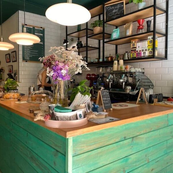 barra interior del establecimiento con madera verda y flores rosas y cafetera